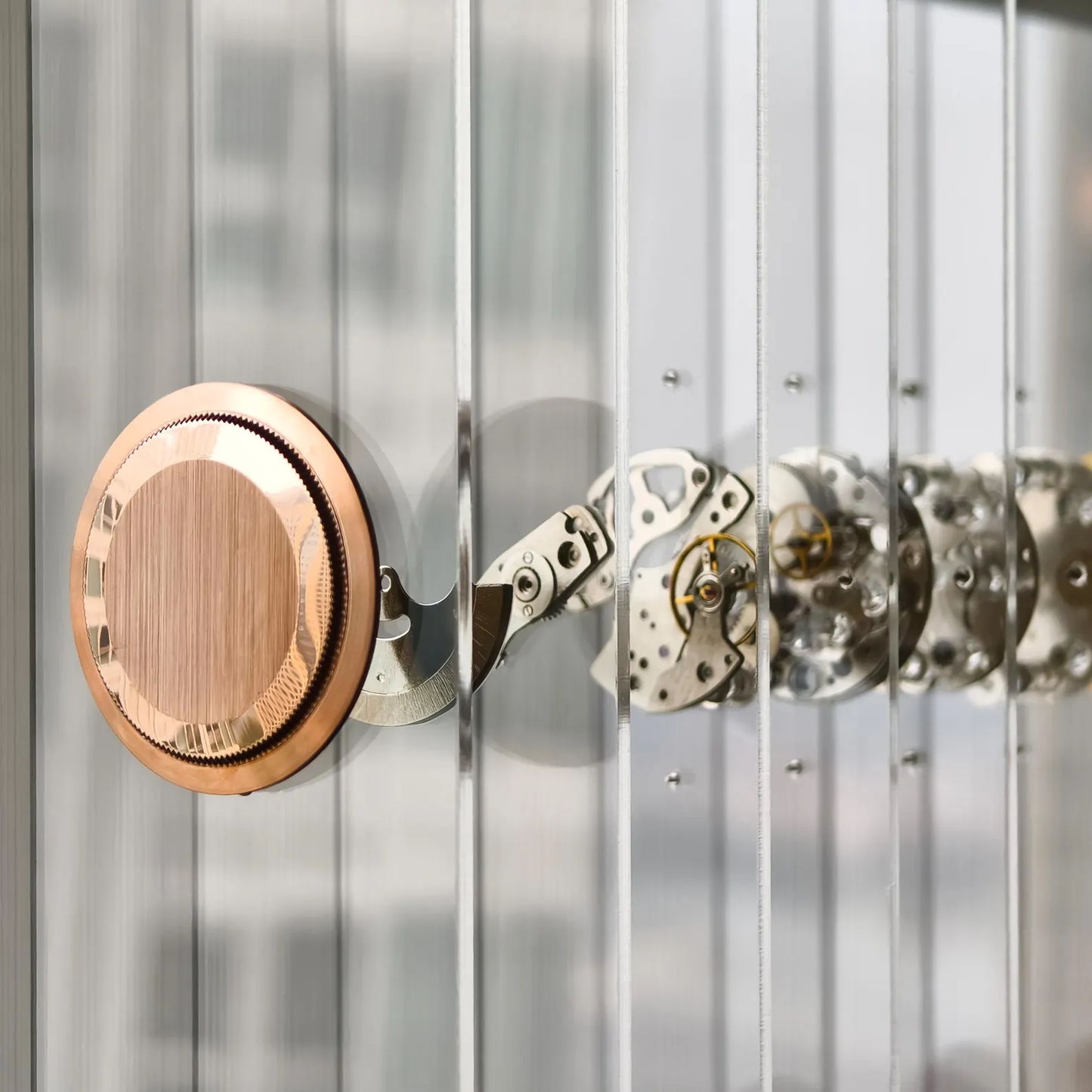 Close-up of a rose gold watch case and metallic gears on fiber glass