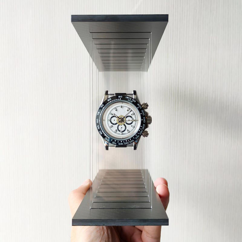 Hand holding a transparent stand with a panda model wristwatch on a white background