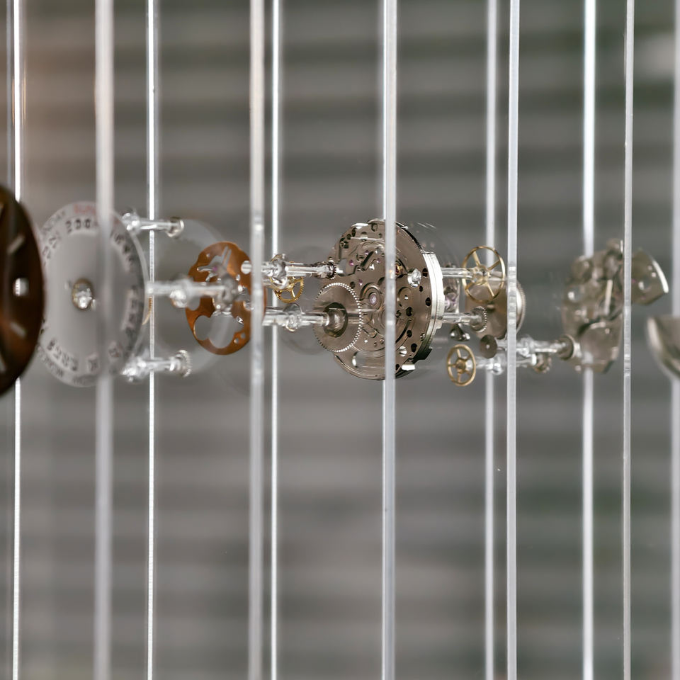 Close-up of mechanical clock gears behind fiber glass