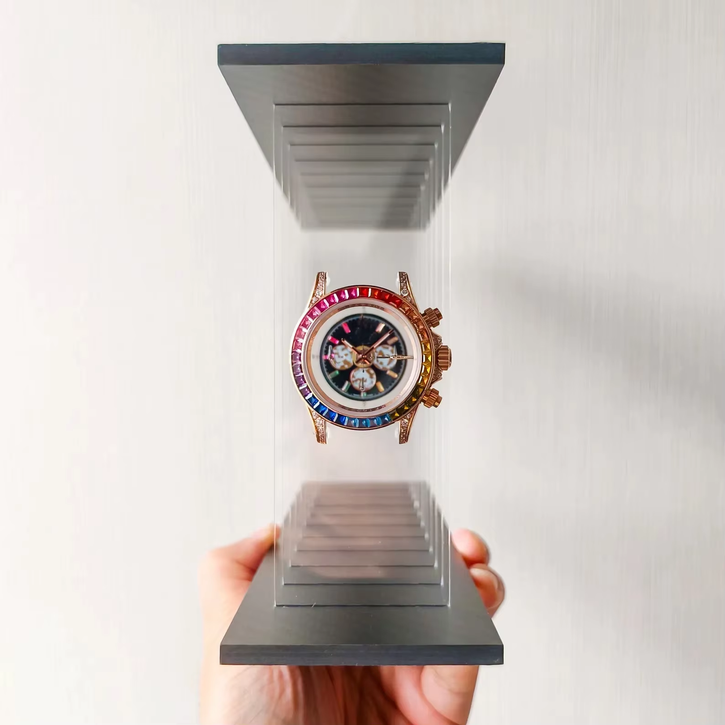 Luxury watch with rainbow face displayed in a clear case 