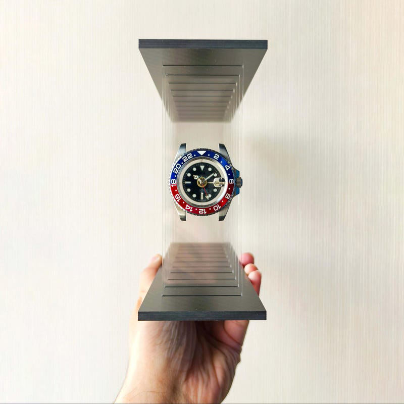 Hand holding a Pepsi model watch on a metallic stand 