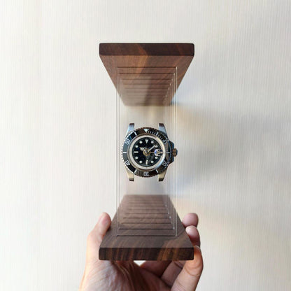 Hand holding a submarine model watch in a wooden display case against a light background